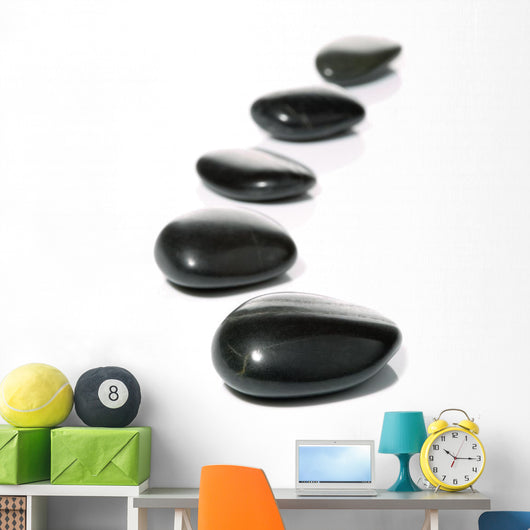 Five black pebbles in a gentle curve on a white surface Wall Mural