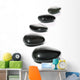 Five black pebbles in a gentle curve on a white surface Wall Mural