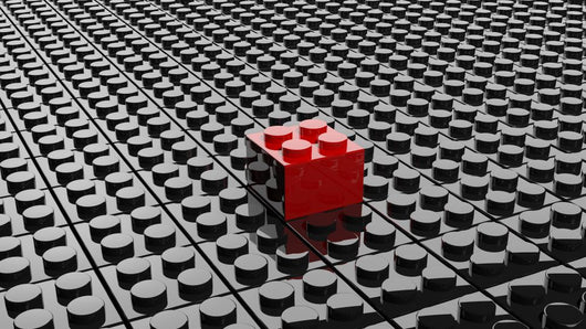 Black lego background with one red block standing out 