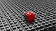 Black lego background with one red block standing out 