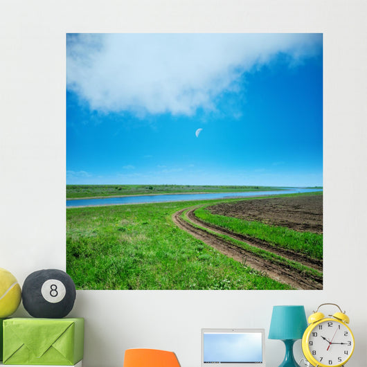 green field and road under cloudy sky in evening 