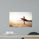 Beautiful surfer girl in the beach with her surfboard at sunset Wall Mural