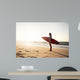 Beautiful surfer girl in the beach with her surfboard at sunset Wall Mural