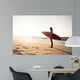 Beautiful surfer girl in the beach with her surfboard at sunset Wall Mural