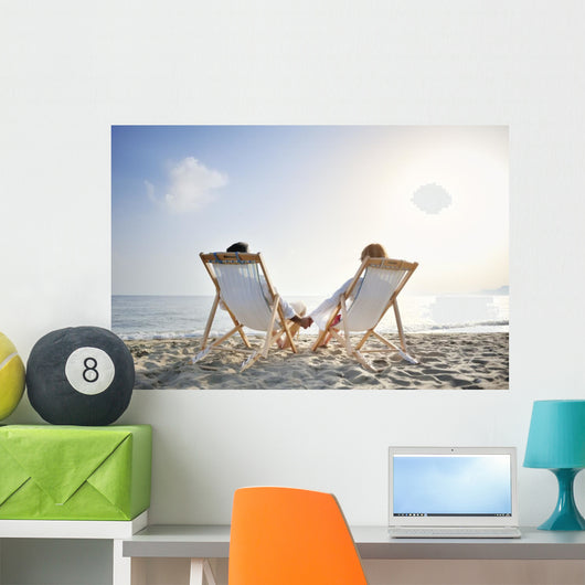 romantic couple on deckchair relaxing on the beach Wall Mural