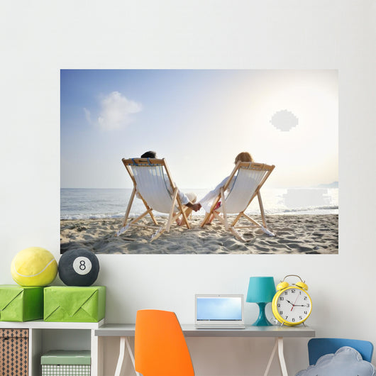 romantic couple on deckchair relaxing on the beach Wall Mural