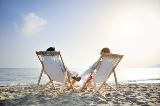 romantic couple on deckchair relaxing on the beach Wall Mural