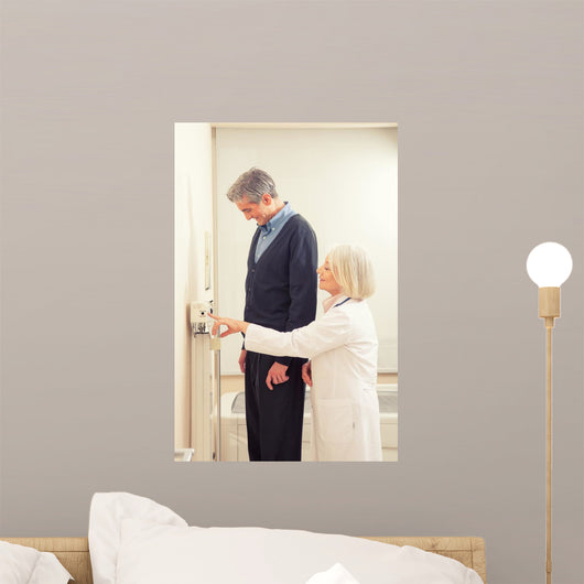 General practitioner measuring male patient's height in hospital Wall Mural