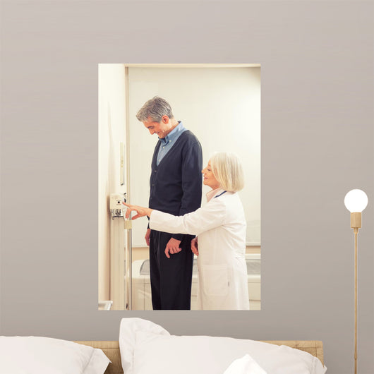 General practitioner measuring male patient's height in hospital Wall Mural