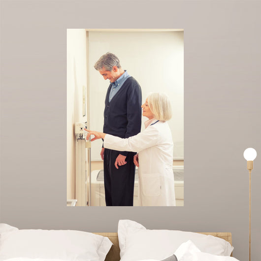 General practitioner measuring male patient's height in hospital Wall Mural