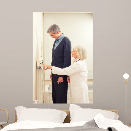 General practitioner measuring male patient's height in hospital Wall Mural