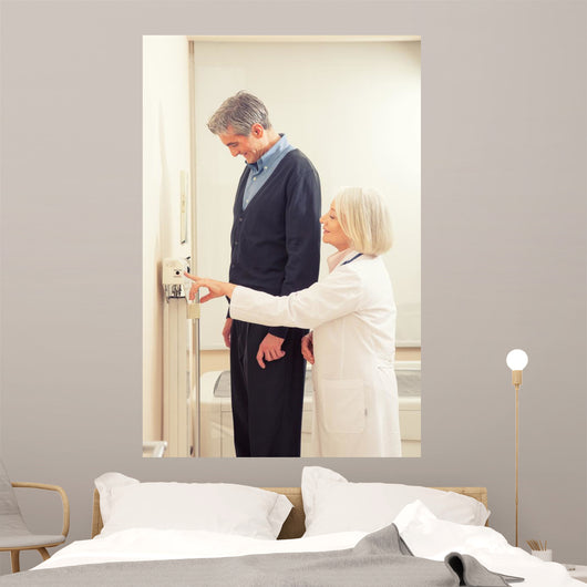 General practitioner measuring male patient's height in hospital Wall Mural