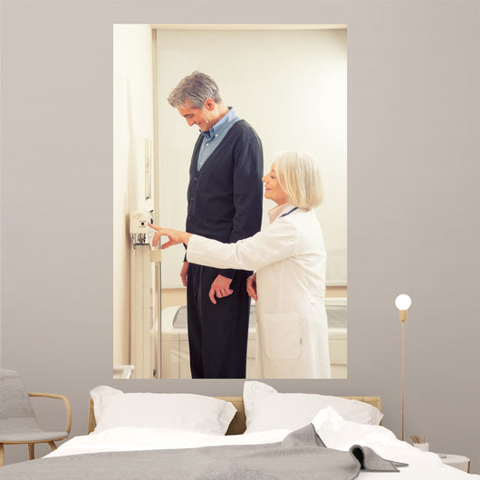 General practitioner measuring male patient's height in hospital Wall Mural