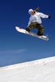 Woman Snowboarder in Flight With Sky Behind Wall Mural