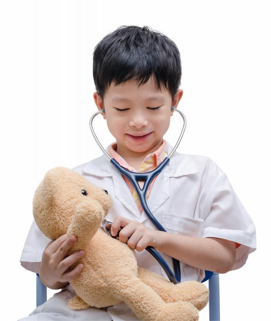 Young Asian doctor boy playing and curing bear toy isolated on w Wall Decal