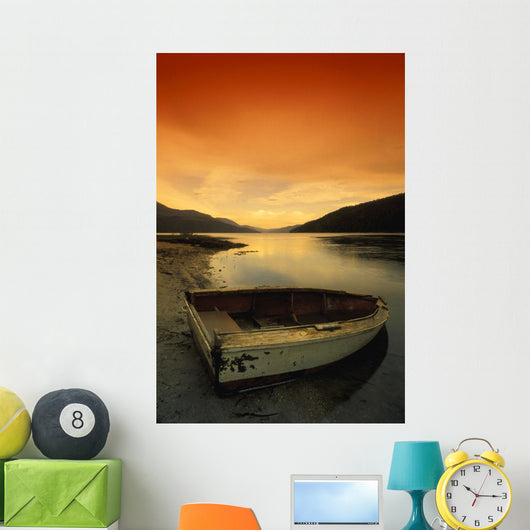 Old Rowboat At Water's Edge With Sunset Background Wall Mural