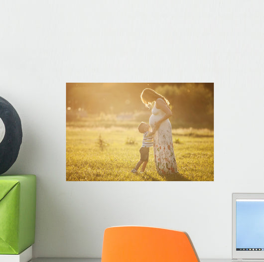 Small boy kissing belly of his pregnant mother outdoors Wall Mural