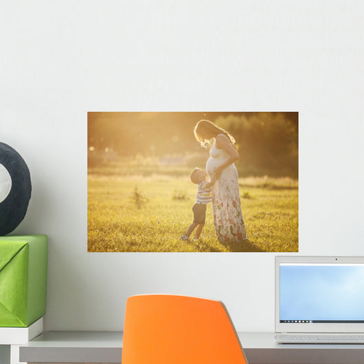 Small boy kissing belly of his pregnant mother outdoors Wall Mural