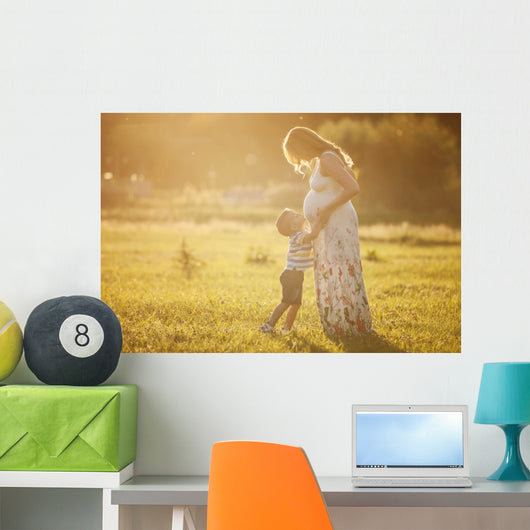 Small boy kissing belly of his pregnant mother outdoors Wall Mural