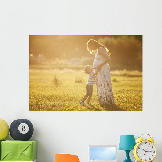 Small boy kissing belly of his pregnant mother outdoors Wall Mural