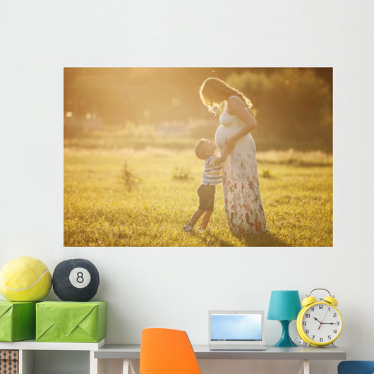 Small boy kissing belly of his pregnant mother outdoors Wall Mural