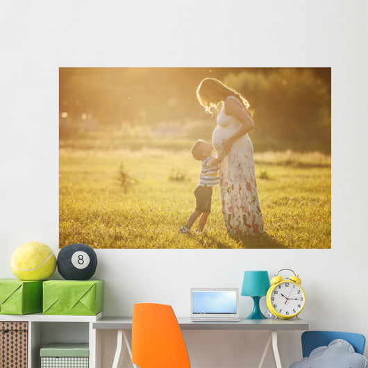 Small boy kissing belly of his pregnant mother outdoors Wall Mural