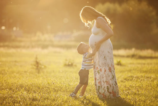 Small boy kissing belly of his pregnant mother outdoors Wall Mural