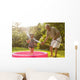Grandparent and grandkid playing with hose Wall Mural