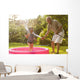 Grandparent and grandkid playing with hose Wall Mural
