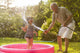 Grandparent and grandkid playing with hose Wall Mural