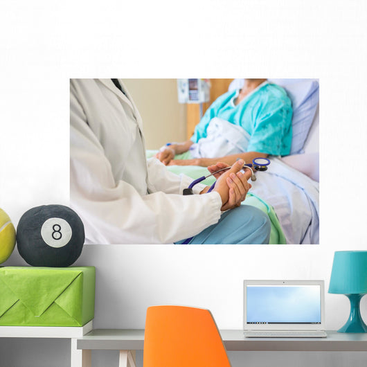 Female Doctor Sitting With Patient On Hospital Bed Wall Mural