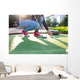 Young woman plays adventure/mini golf in summer evening Wall Mural