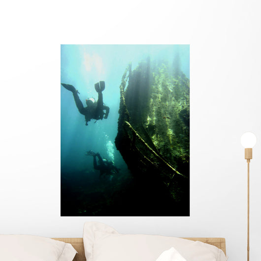 Wreck with sunbeams showing bow of boat and divers Wall Mural