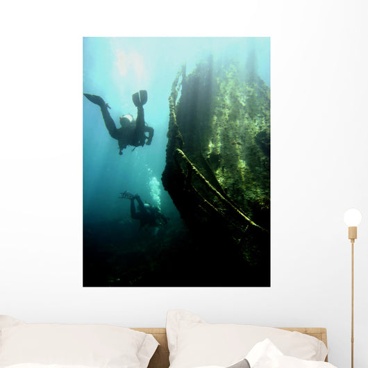 Wreck with sunbeams showing bow of boat and divers Wall Mural