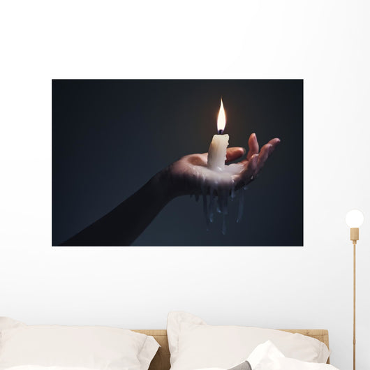 Holding a candle on a dark background. Wall Mural