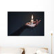 Holding a candle on a dark background. Wall Mural