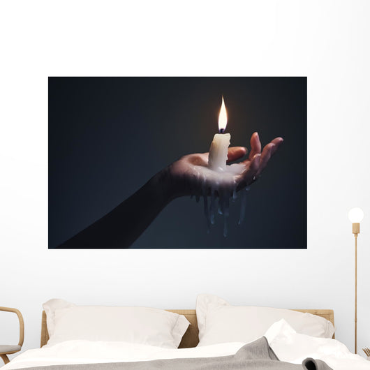 Holding a candle on a dark background. Wall Mural