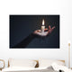 Holding a candle on a dark background. Wall Mural