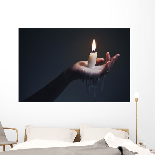 Holding a candle on a dark background. Wall Mural