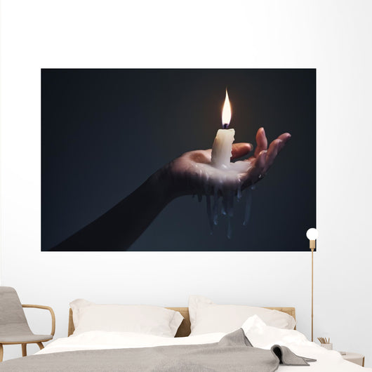 Holding a candle on a dark background. Wall Mural