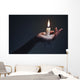 Holding a candle on a dark background. Wall Mural