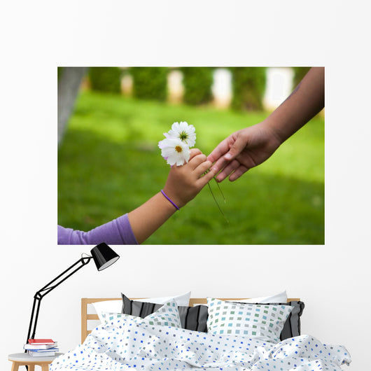 Child's hand giving flowers to her friend Wall Mural