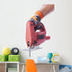 hand in a glove holds a working electric jig saw Wall Decal