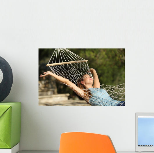 Happy woman relaxing on a hammock on holidays and raising arms Wall Mural
