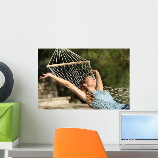 Happy woman relaxing on a hammock on holidays and raising arms Wall Mural