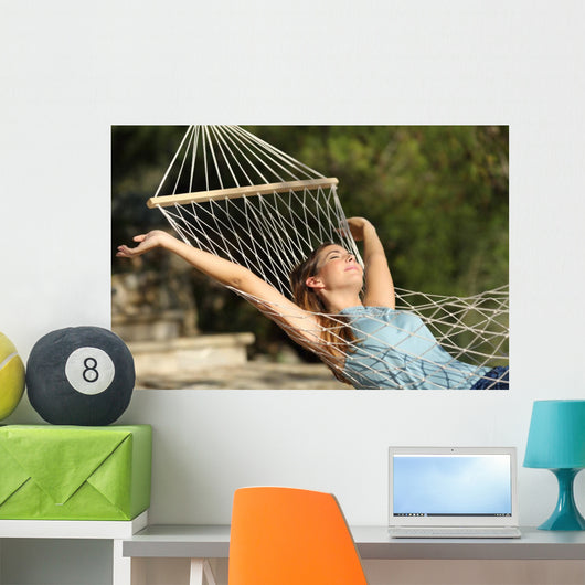 Happy woman relaxing on a hammock on holidays and raising arms Wall Mural