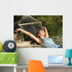 Happy woman relaxing on a hammock on holidays and raising arms Wall Mural