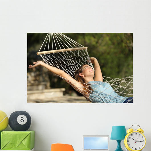 Happy woman relaxing on a hammock on holidays and raising arms Wall Mural
