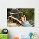 Happy woman relaxing on a hammock on holidays and raising arms Wall Mural