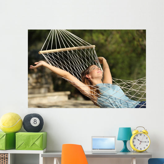 Happy woman relaxing on a hammock on holidays and raising arms Wall Mural